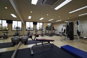 A gym with exercise equipment, large windows, and a view of the outdoors.