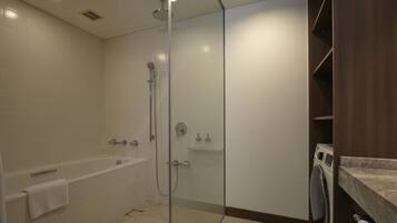 A modern bathroom with a glass-enclosed shower, a bathtub, and a built-in washing machine.