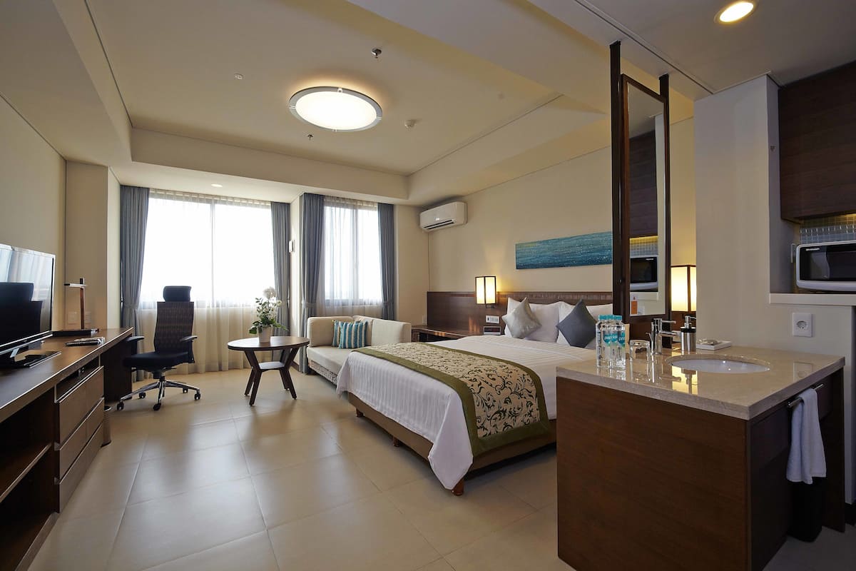 Een hotelkamer met een bed, bureau, stoel en een klein tafeltje.