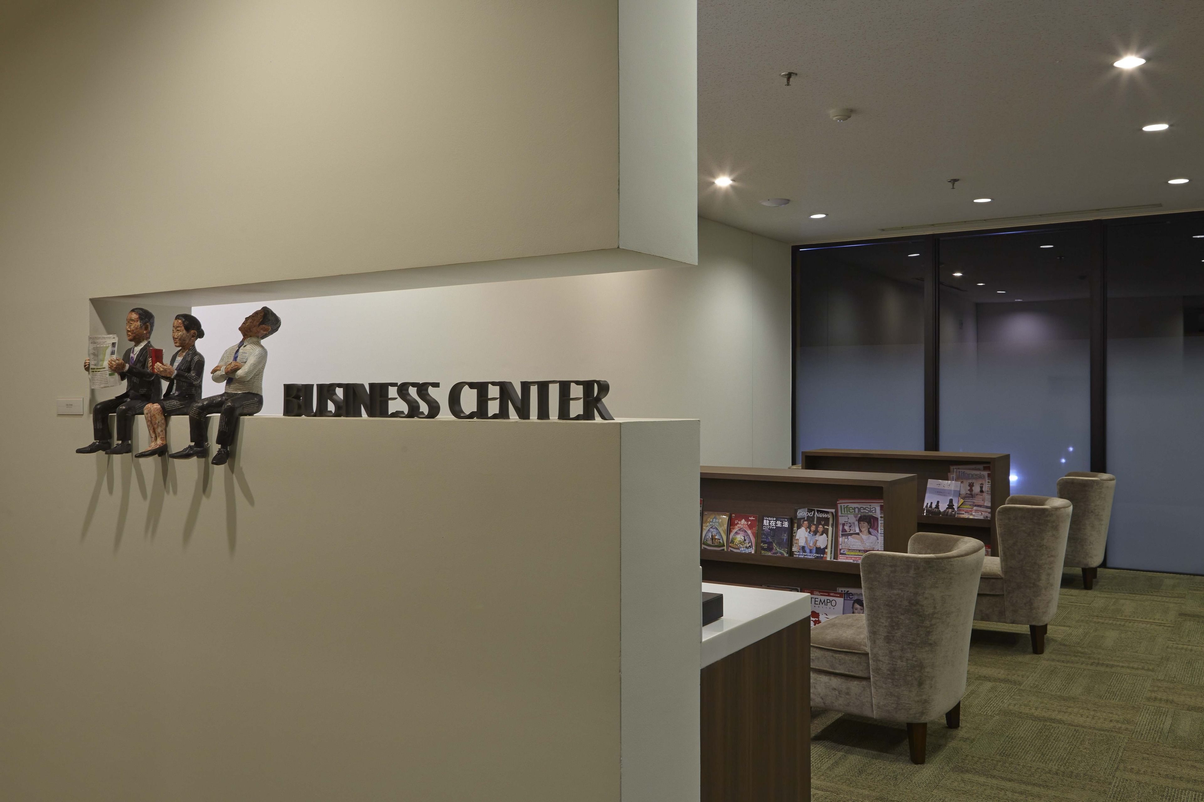 A business center with a reception desk, seating area, and a wall-mounted display of people.