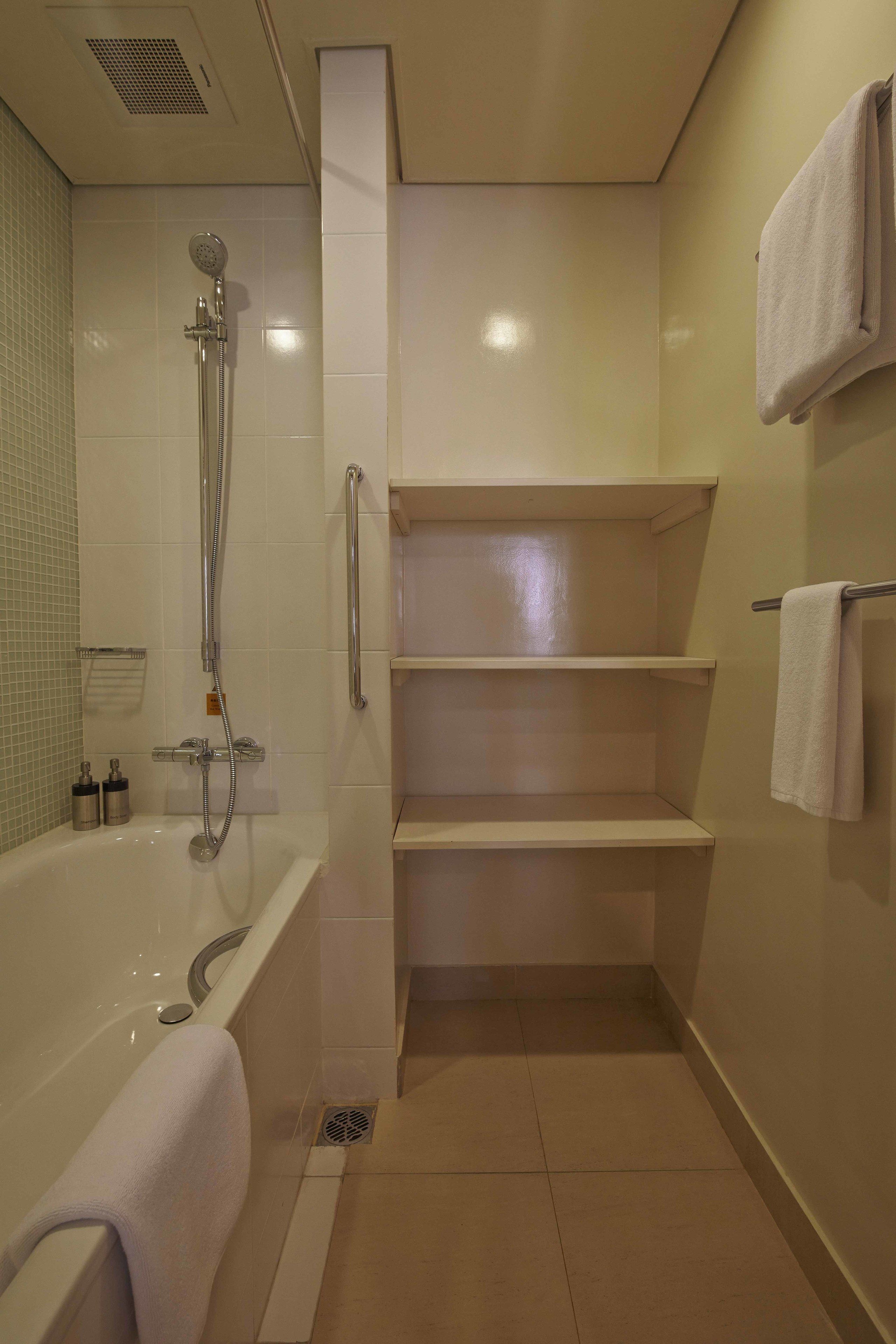 Un baño moderno con bañera, ducha con cabezal de mano y estantes empotrados.