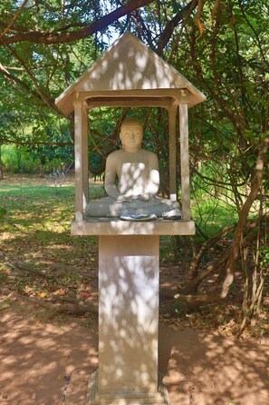 A Buddha statue in a gazebo-like structure surrounded by trees. - The Other Corner (Habarana)
