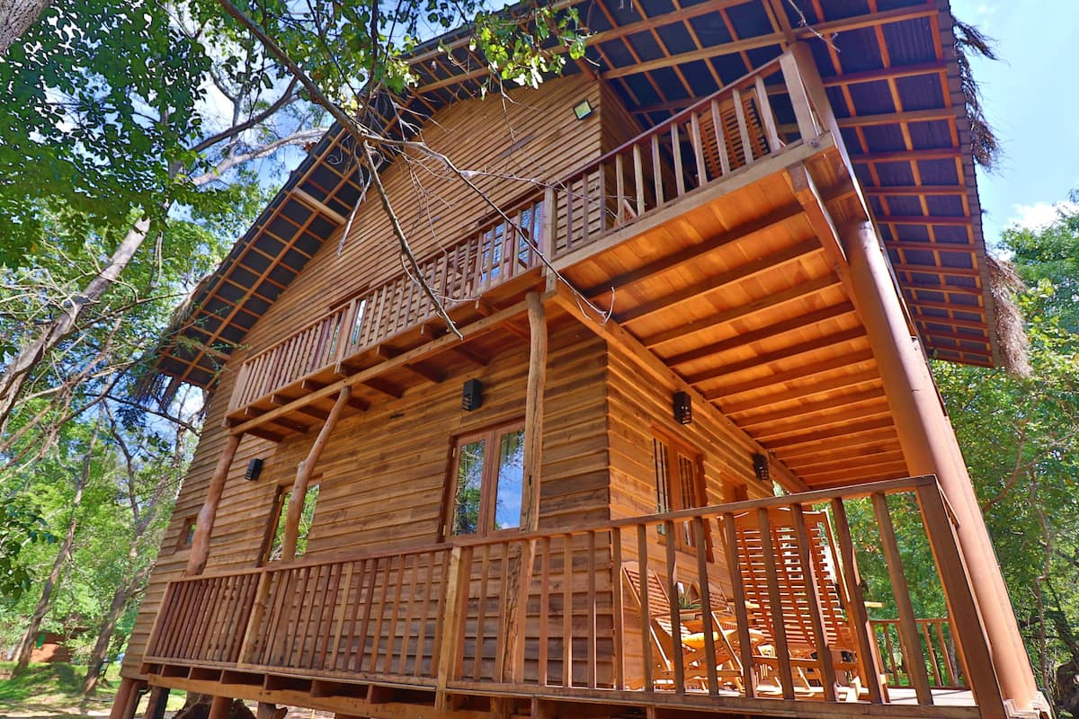 A wooden cabin with a balcony and a staircase leading to the upper level.