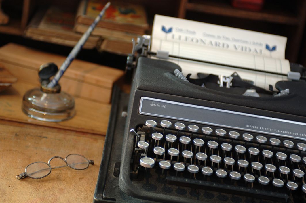 Una máquina de escribir antigua con una etiqueta que dice "Studio 46" y "Hispano Vidal" sobre una superficie de madera.
