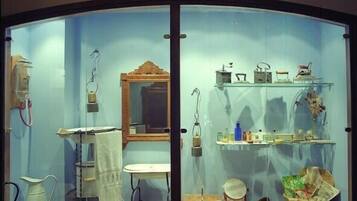 Una exposición de museo con objetos antiguos de cocina, incluyendo un lavamanos, estufa y diversos utensilios.