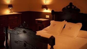 A hotel room with a wooden headboard, a bedside table, a lamp, and a nightstand.