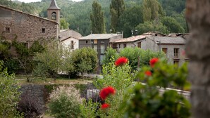 A rustic village with stone buildings, a church tower, and lush greenery. - Casa Leonardo (Senterada)
