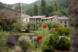 A rustic village with stone buildings, a church tower, and lush greenery.