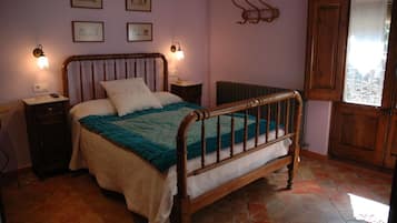 Un dormitorio con cama de madera, dos mesitas de noche, un radiador y una ventana con vistas.