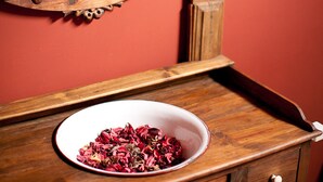 A wooden vanity with a mirror, a bowl of dried flowers, and a candle holder. - Casa Leonardo (Senterada)