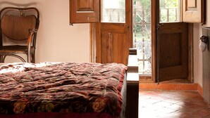 A bedroom with a bed, a chair, and an open door leading to a balcony. - Casa Leonardo (Senterada)