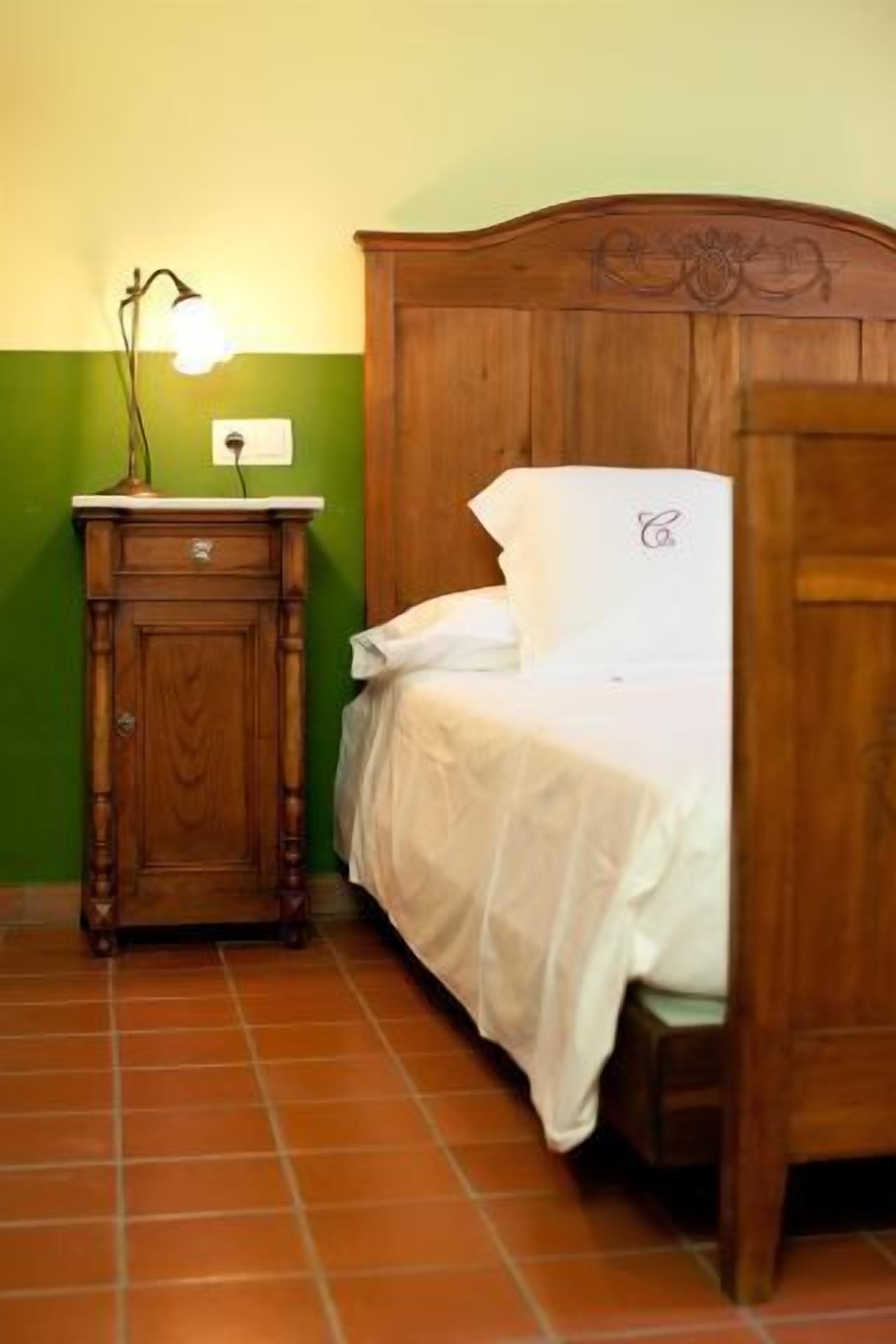 A single bed with a wooden headboard, a nightstand with a lamp, and a green wall.