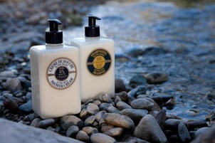 Dos botellas de crema de ducha sobre una superficie rocosa.