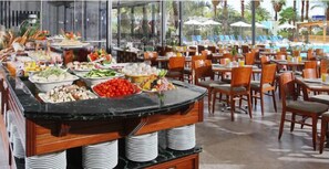 A buffet setup with various food items and a poolside dining area. - Americana Hotel (Eilat)