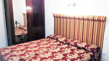 Um quarto com um espelho grande, uma cama com cabeceira listrada e uma mesa de cabeceira pequena.