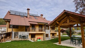 A two-story house with a red-tiled roof, a stone facade, and a wooden balcony. - El Casar del Puente (Boca de Huergano)