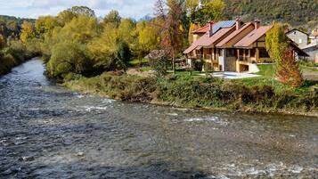 Un río serpenteando por un valle con casas en la ribera derecha.