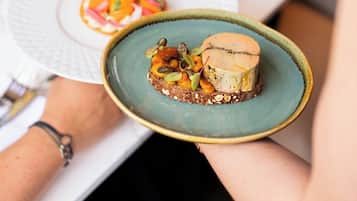 Une personne tenant une assiette avec un dessert et une autre assiette avec une salade.