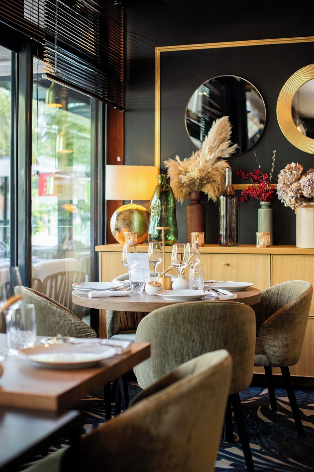 A dining area with round tables, chairs, and a variety of decorative items including vases and a mirror.