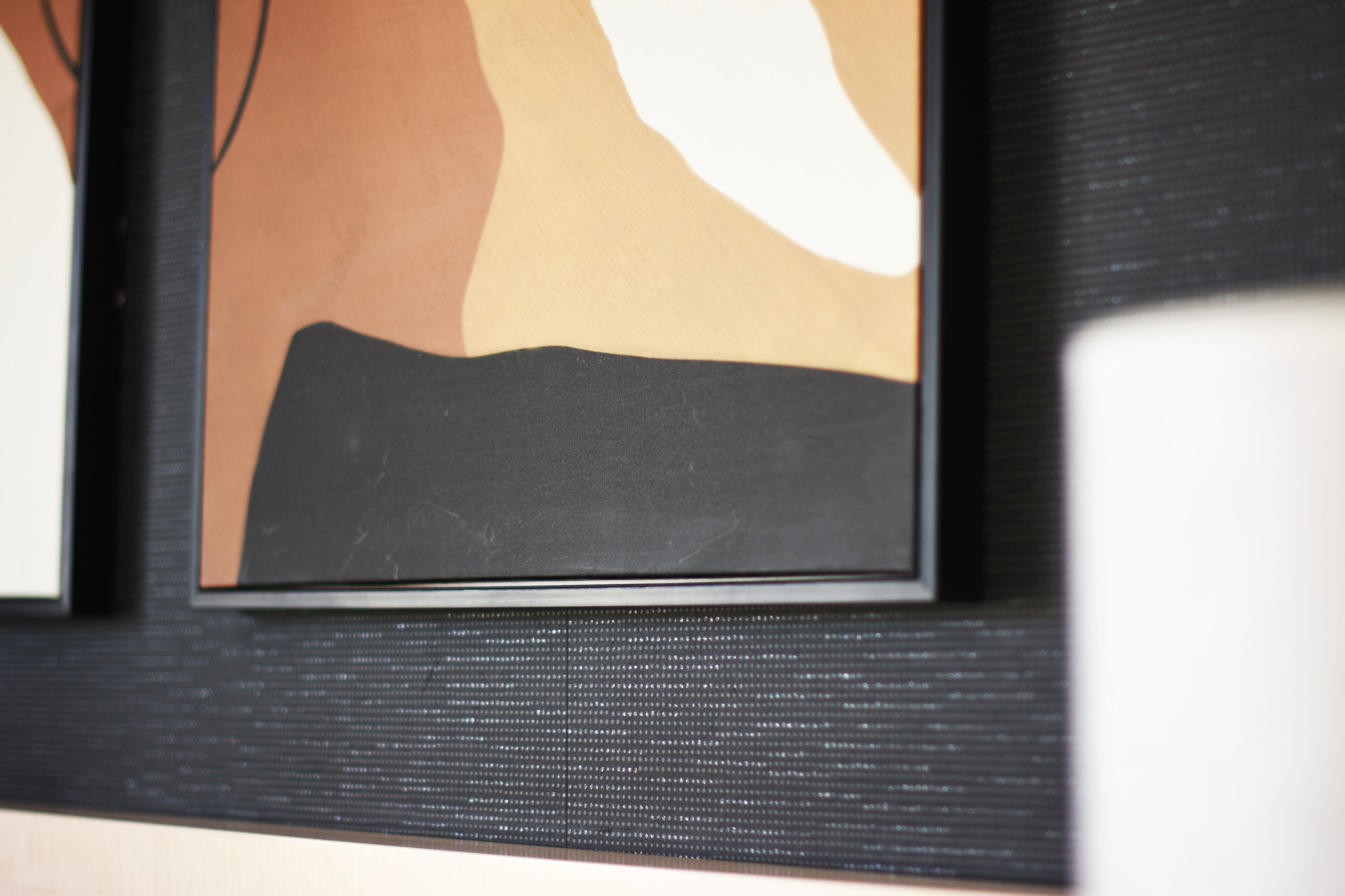 Un quadro astratto incorniciato, con una combinazione di colori marrone, beige e nero.
