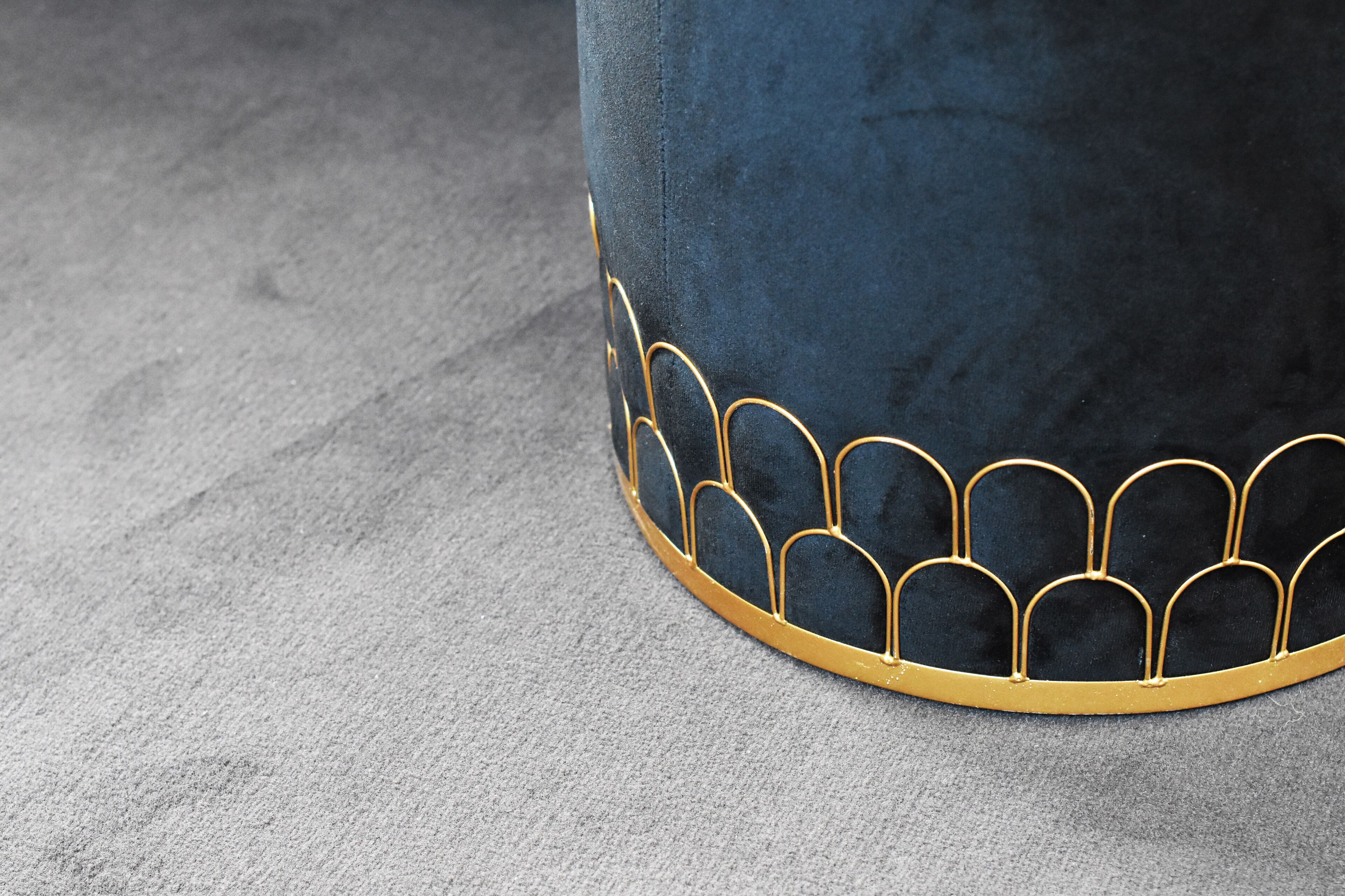 A close-up of a dark blue upholstered chair with a gold trim and a patterned design on the seat.