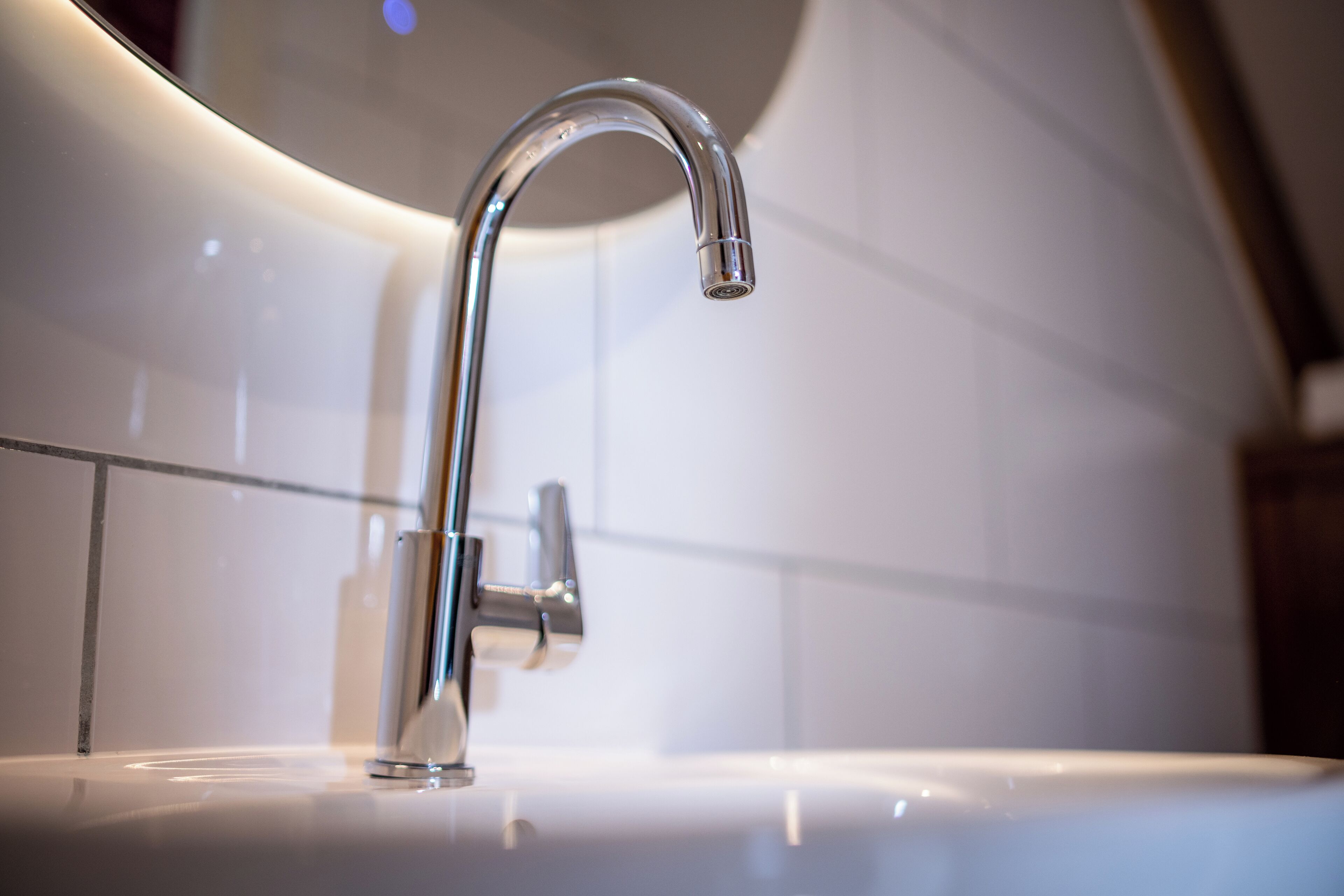 Un bagno moderno con un rubinetto cromato e piastrelle bianche.