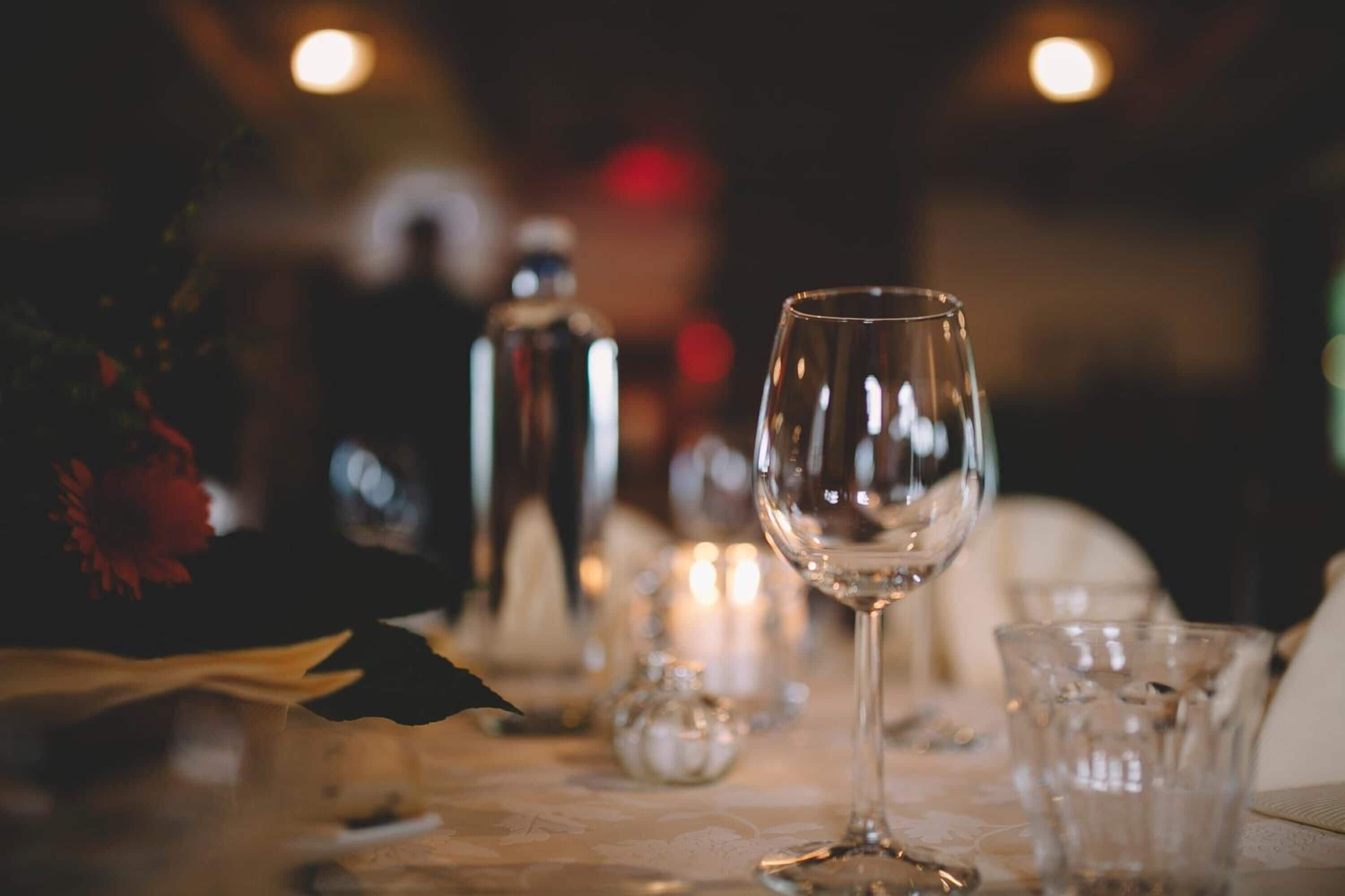 Mesa posta para refeição com uma taça de vinho, um copo de água e um saleiro e pimenteiro.