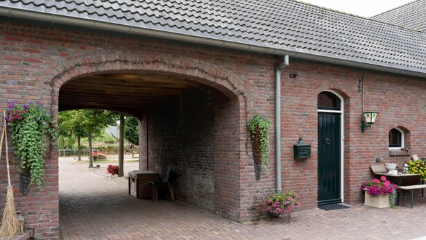 A brick building with a covered entrance, outdoor seating, and potted plants.