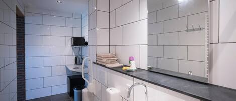 A modern bathroom with a white sink, a mirror, and a toilet.