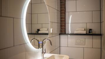 A modern bathroom with a large mirror, a sink, and a towel rack.
