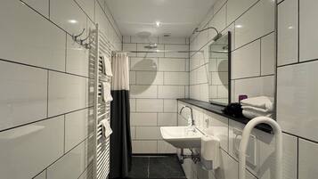 A modern bathroom with white tiles, a toilet, a sink, and a shower.