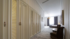 Et hotelværelse med et stort skab, seng, siddeområde og en lysekrone.