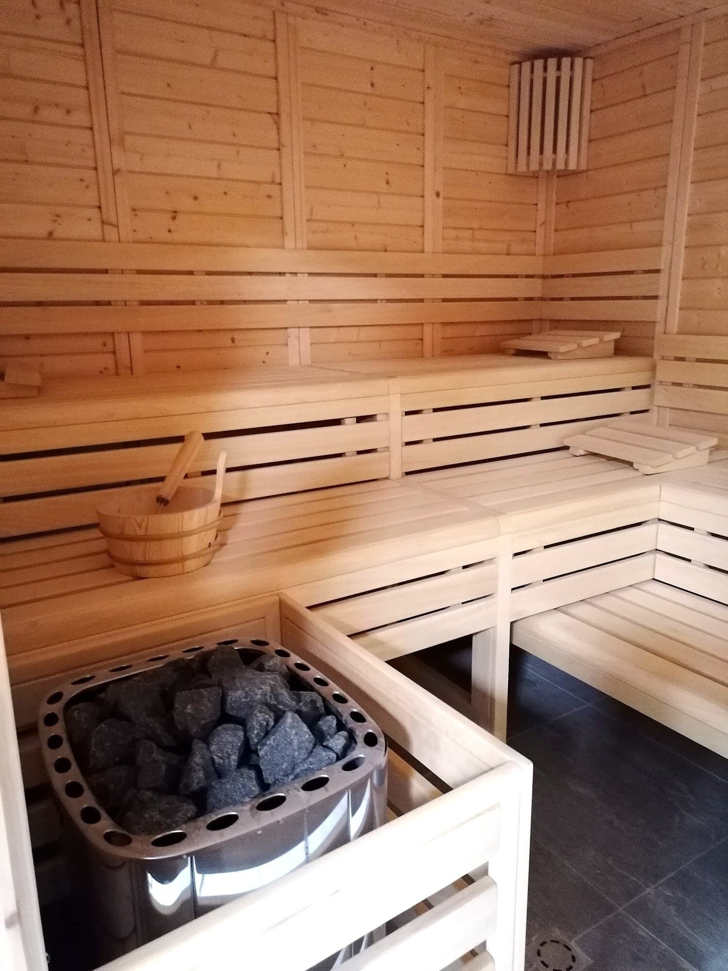 A sauna with wooden benches, a stone basin, and a ventilation system.