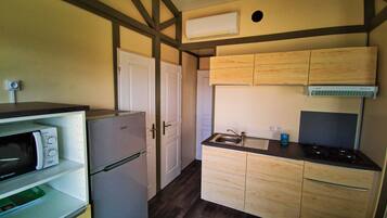 Cocina compacta con refrigerador, microondas, lavamanos y estufa.