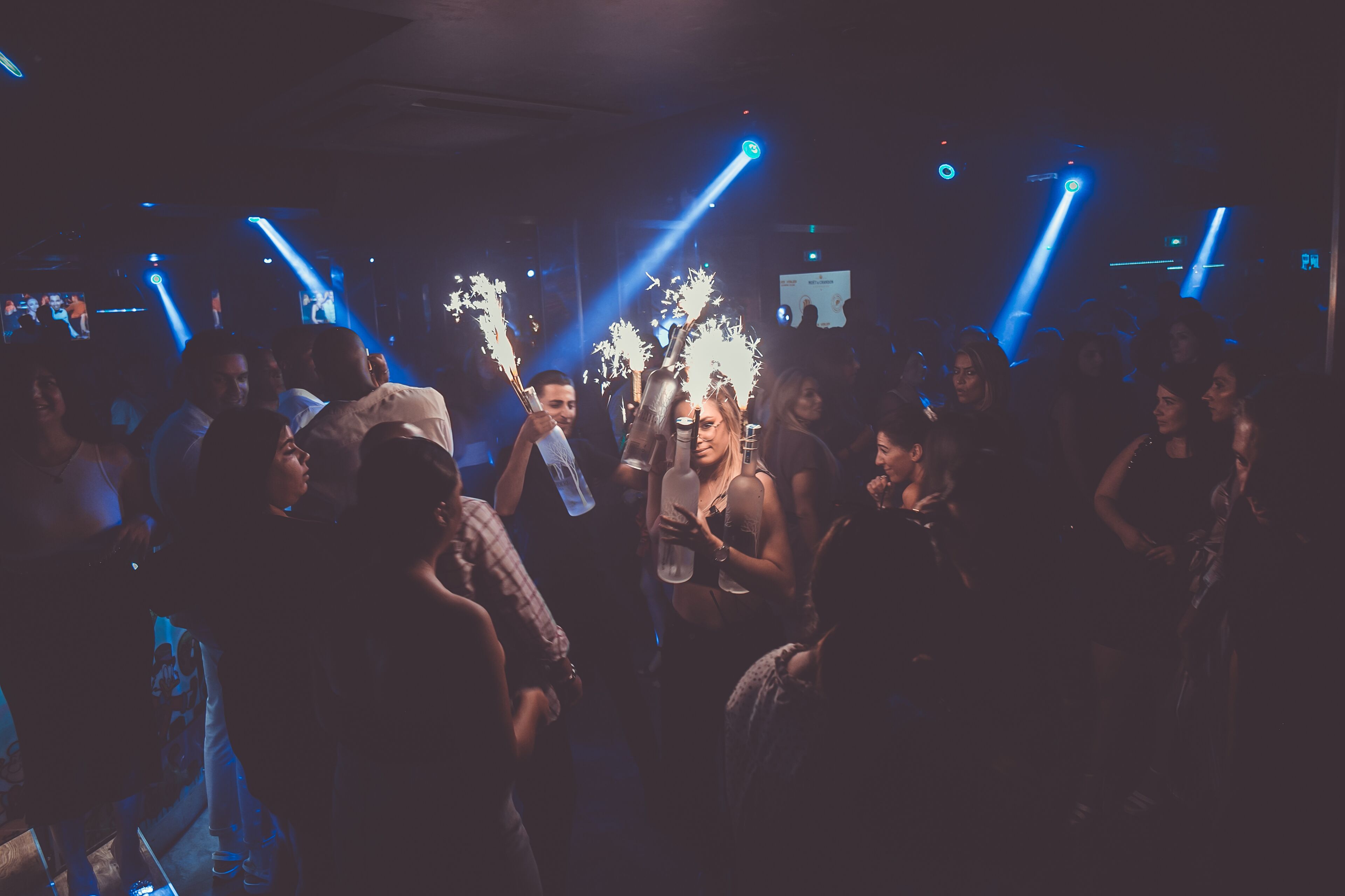 A crowded indoor space with people holding illuminated objects, suggesting a social event or party.