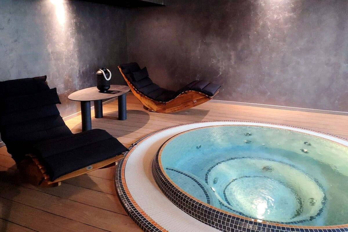 Ein Wellnessbereich mit Whirlpool, zwei Liegen und einem kleinen Tisch.