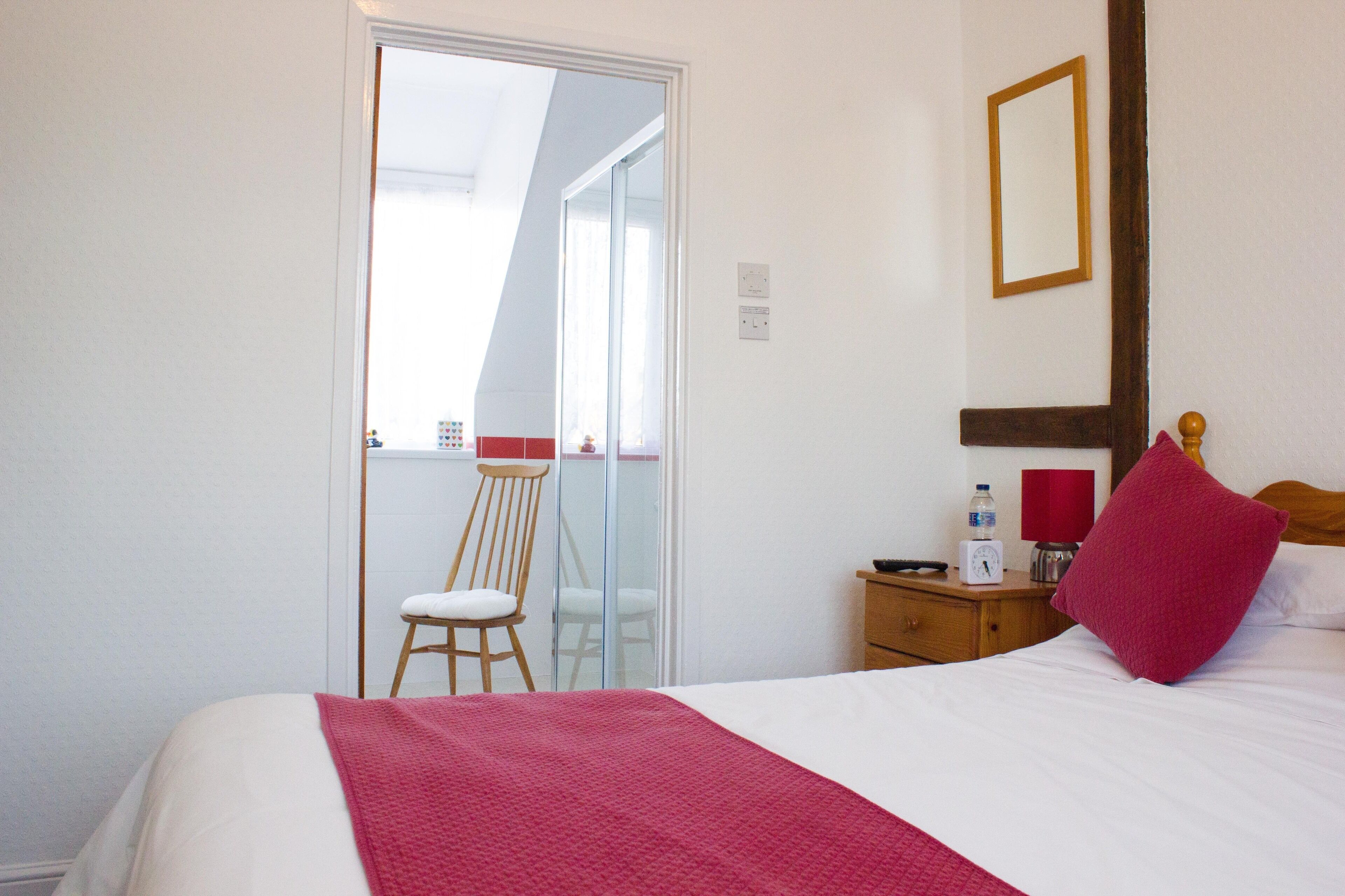 Ein Hotelzimmer mit Bett, Stuhl, Nachttisch und Spiegel an der Wand.