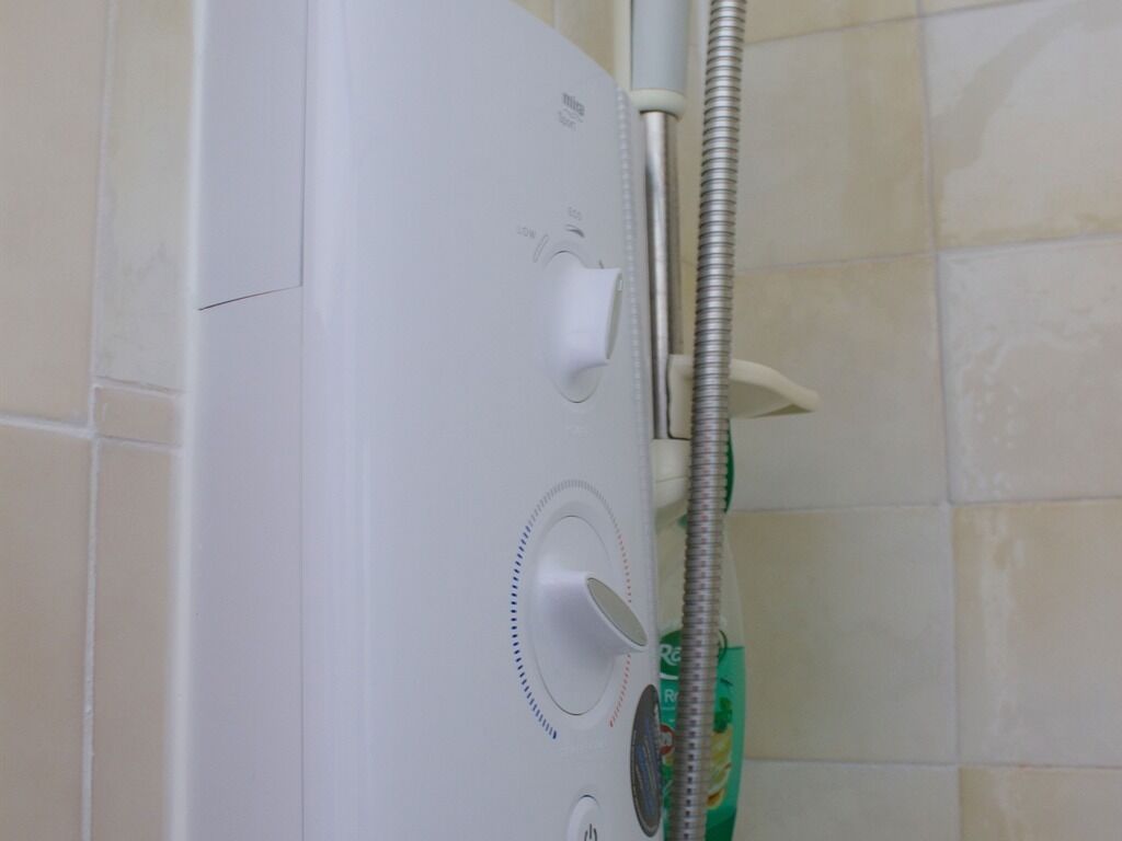 Ducha blanca con cabezal de ducha manual y un mando.