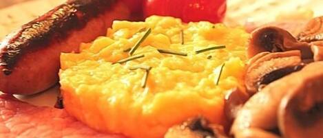 A plate with grilled meat, mushrooms, and a yellow dish, possibly mashed potatoes, garnished with herbs.