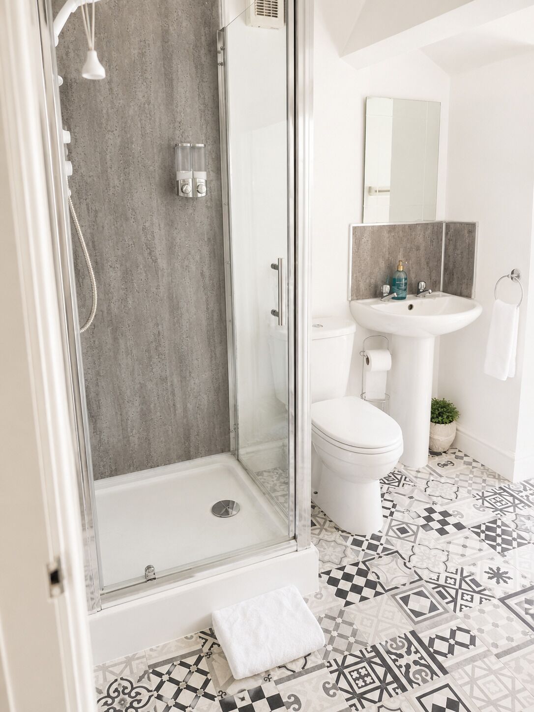 Une salle de bain avec une douche à parois de verre, un lavabo blanc et des toilettes.