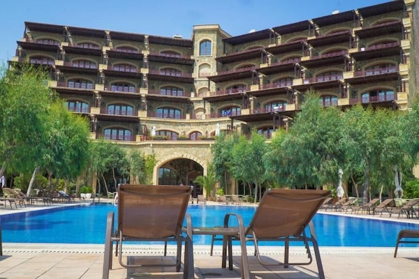 Una piscina al aire libre, sombrillas, sillones reclinables de piscina