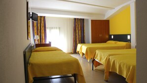 Habitación de hotel con dos camas individuales, televisión y ventana con cortinas.