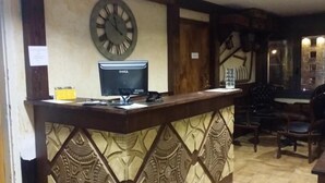 Un mostrador de recepción con un reloj, una computadora y una silla.