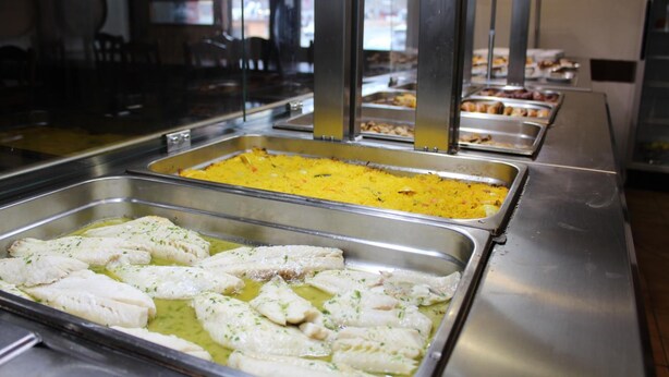 Un bufé con diversas opciones de comida, incluyendo pescados y platos de arroz.
