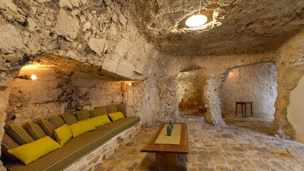 A cave-like interior with a sofa and a wooden table. - Masseria Lamiola Piccola (Ostuni)