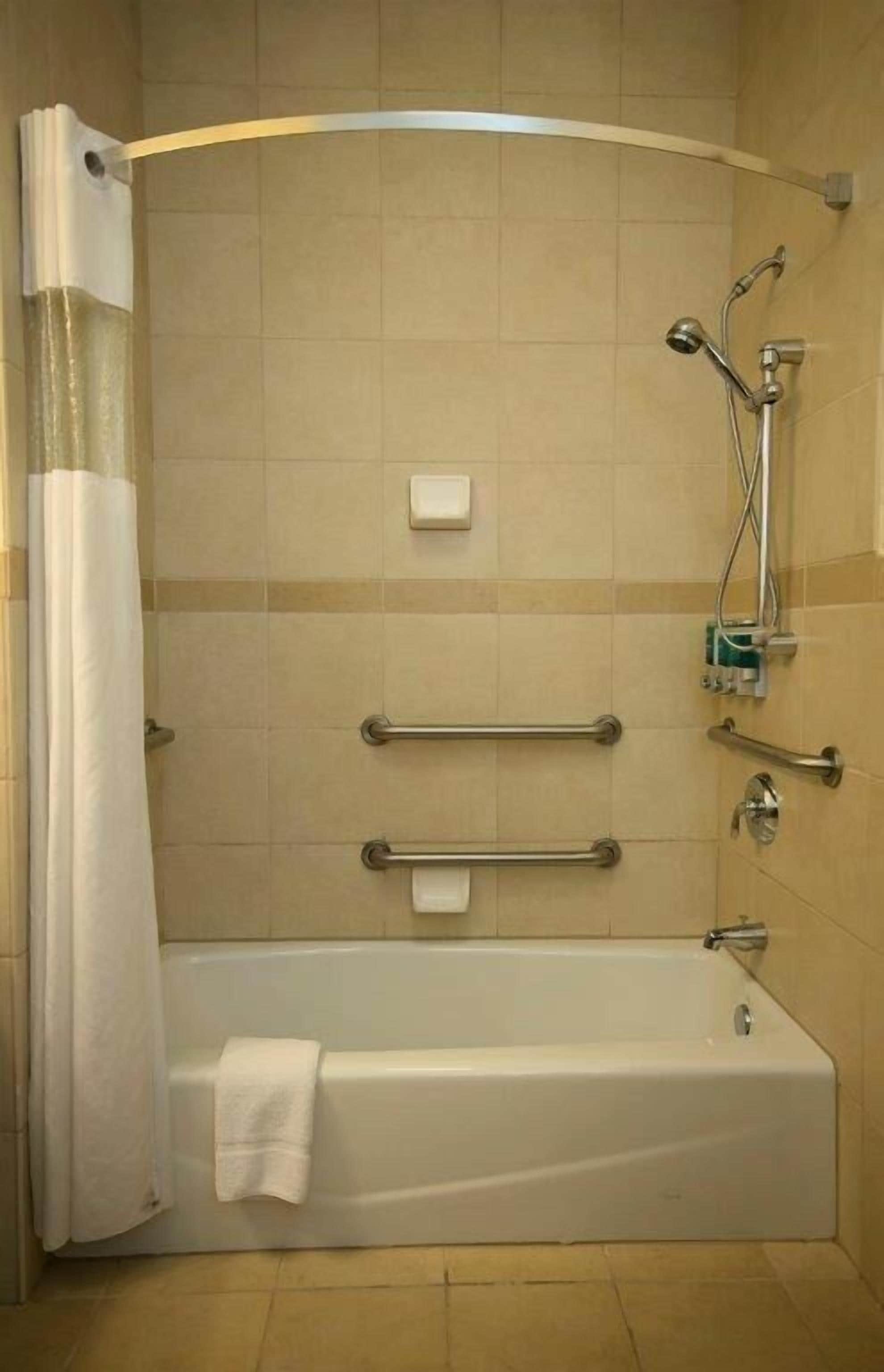 Ducha estándar con mampara de vidrio curva, cabezal de ducha manual y grifo monomando.