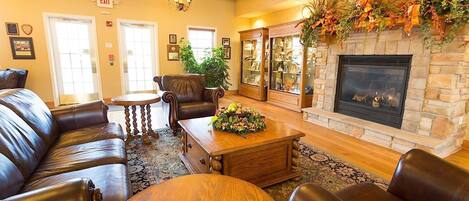 A cozy lounge area with leather sofas, a wooden coffee table, and a stone fireplace.
