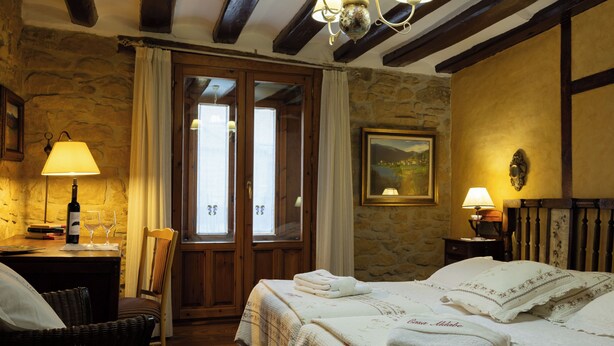 Une pièce confortable avec un lit, une chaise, un bureau et une fenêtre avec des rideaux.