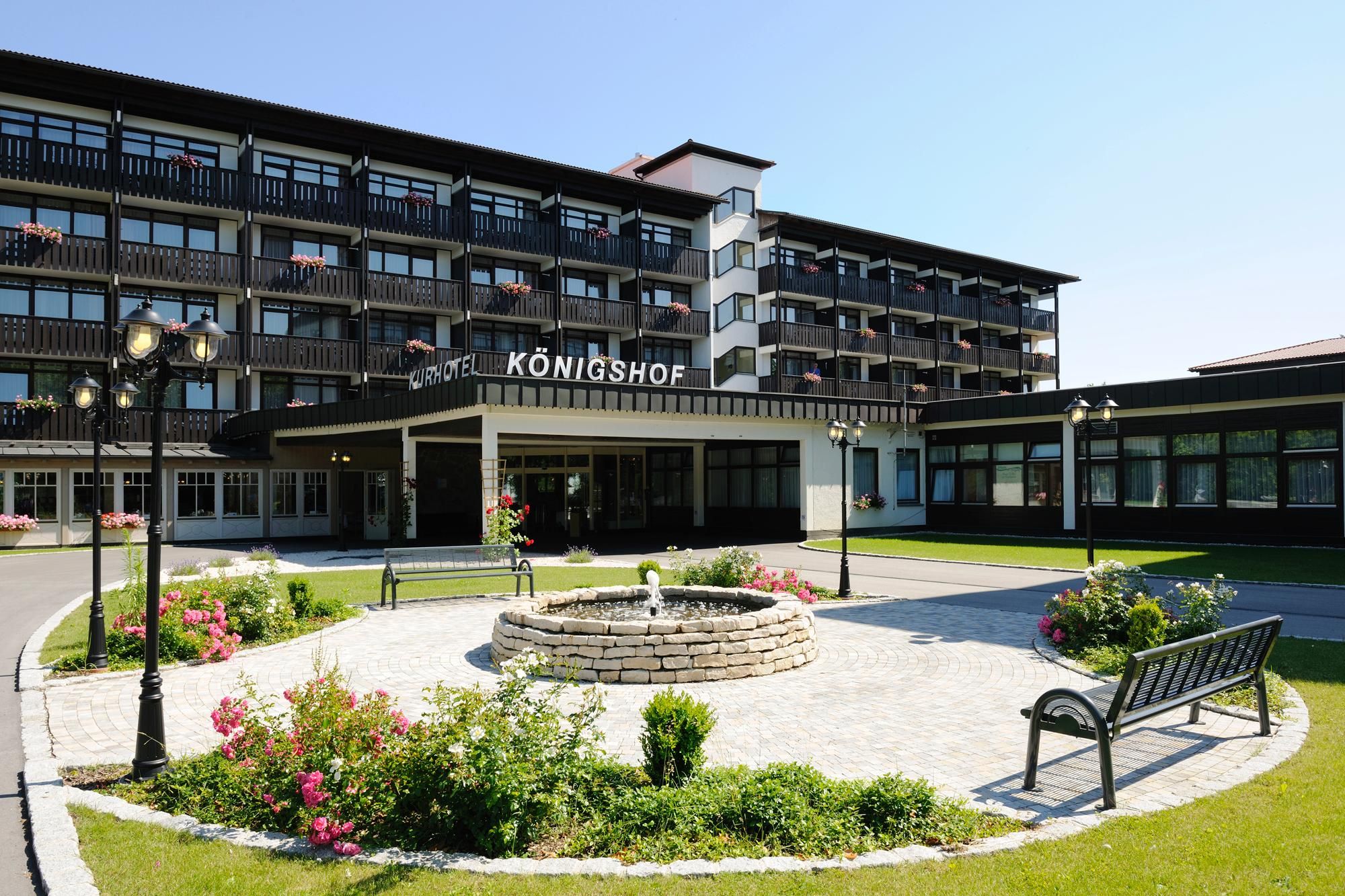 Ein Hotel mit moderner Fassade, einem zentralen Innenhof mit Brunnen und einem gepflegten Garten.