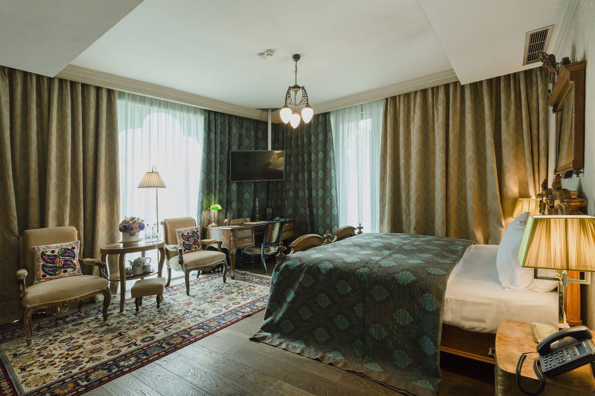 Una habitación de hotel con una cama grande, un escritorio con una silla, un televisor y un teléfono.